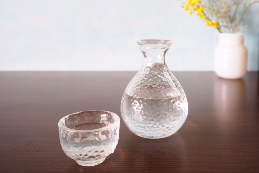 透明な徳利・おちょこに入った日本酒と花瓶
