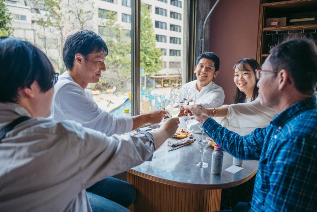 日本盛「はなや香」をワイングラスに注ぎ乾杯する人たち