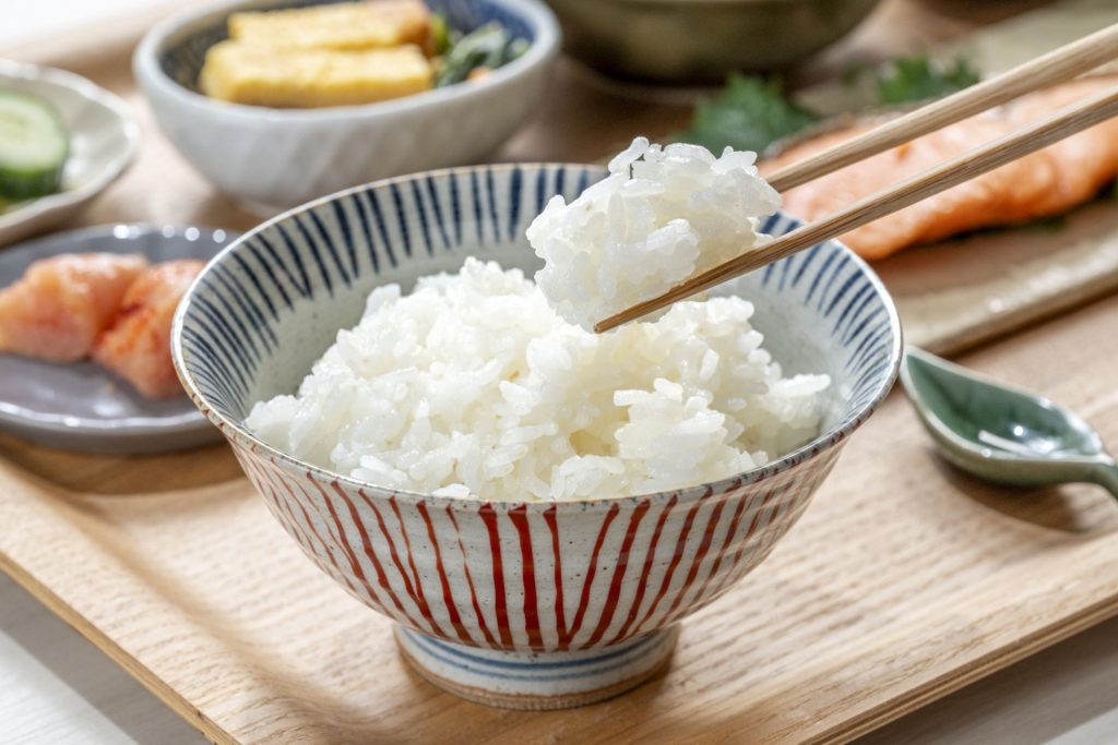 お惣菜と箸で持ち上げた白米